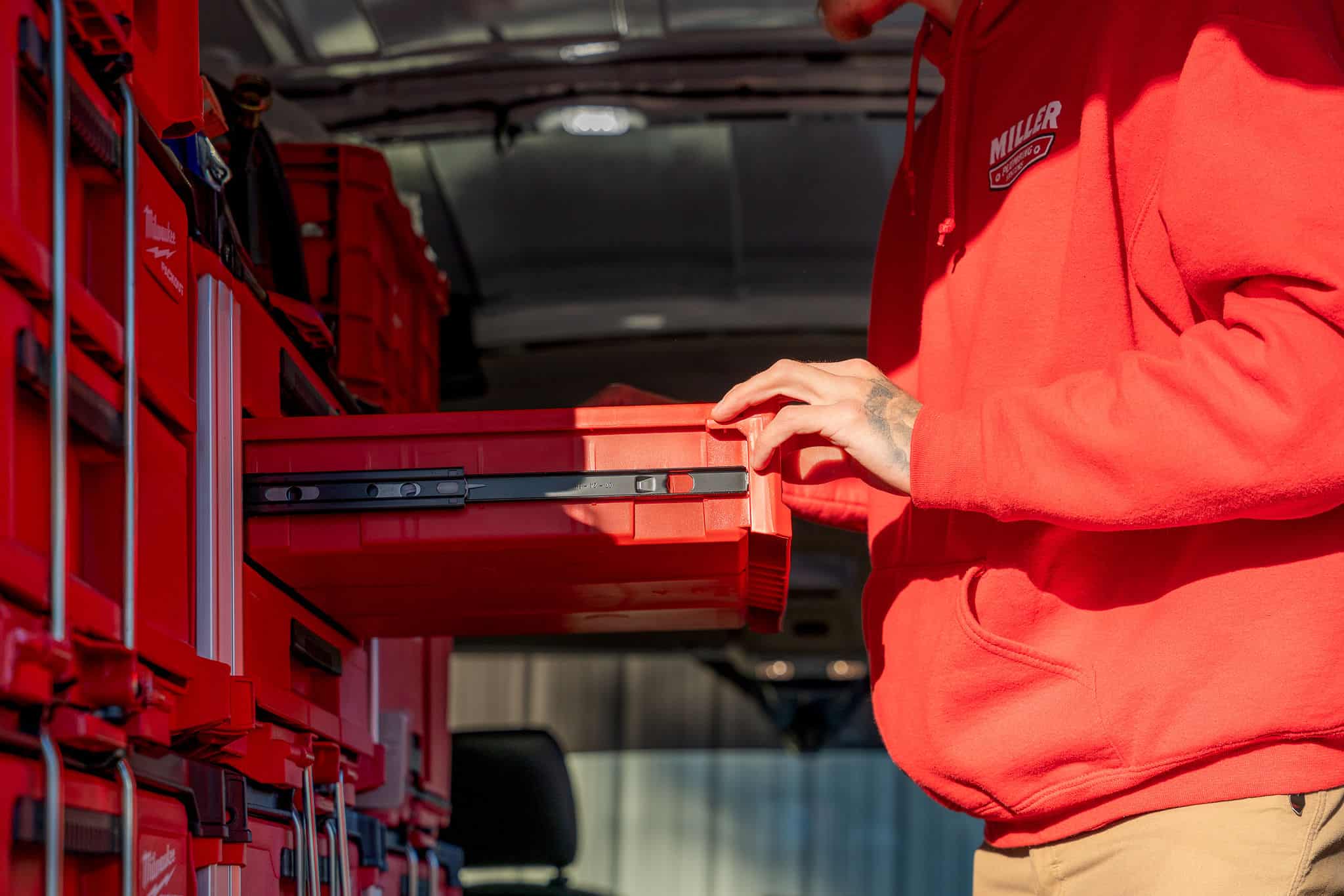 A Miller Plumbing technician pulling out a parts drawer inside the truck.