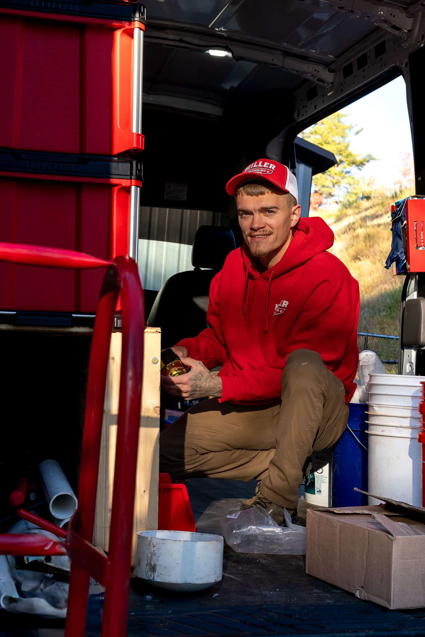 A Miller Plumbing crew member working on a fitting in the back of the service truck.